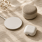 Wireless earbuds, charging pad and speaker on cream linen