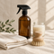 Amber spray bottle, wooden brush and cotton cloths on linen