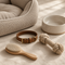 Dog bed, collar, rope toy and pet bowl on cream linen
